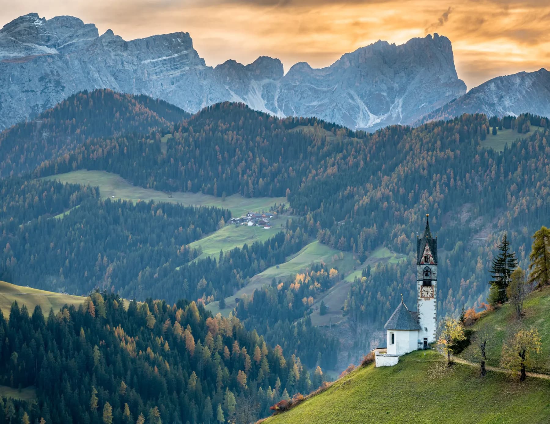 Church steeple among homes in a wooded valley